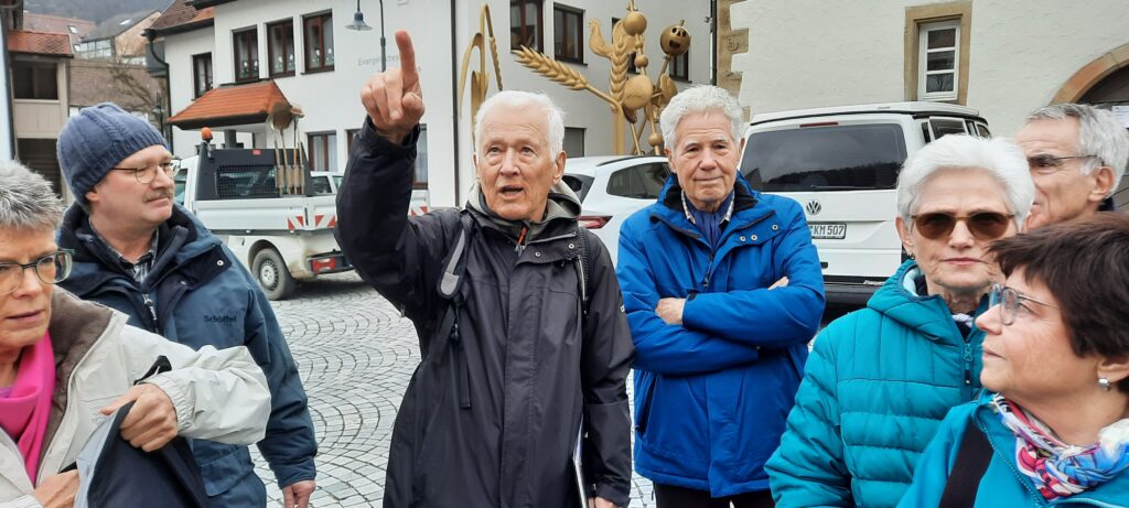 Wanderführer Horst Seidner gibt die Richtung vor - Auf dem Marktplatz in Mönsheim am 28. Februar 2024